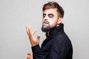 halloween makeup on a bearded man who gestures at the camera photo