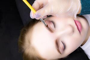 applying hair dye to the eyebrows of the model photo