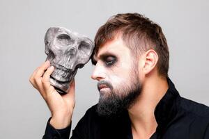 a man in the style of undead makeup holds a shard in his hand photo