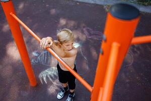 Top view of a sporty teenager boy who is standing in front of a horizontal crossbar. Street workout on a horizontal bar in the school park. photo