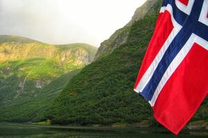 View of Geirangerfjord from the boat with Norwegian flag, Western fjords, Norway. Scandinavian mountains of Sunnylvsfjorden canyon photo