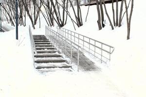 Stairs and ramp with metal railings for the passage of strollers and wheelchairs in public park at winter time. Comfortable barrier-free urban environment in city. Pathway for people with disabilities photo