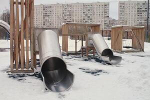 de madera patio de recreo hecho de natural Respetuoso del medio ambiente material en público ciudad parque con nieve a invierno tiempo. moderno la seguridad niños al aire libre equipo. invierno actividades. niños descanso y juegos en abierto aire foto