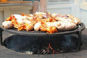 frito salchichas y pollo alas en parilla parrilla en el aldea. fritura carne en abierto fuego. parilla fiesta en patio interior de país casa cabina. calle comida festival. hogar Cocinando exterior. picnic hora foto