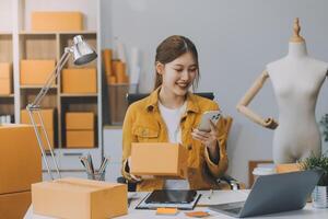 Las pymes asiáticas usan computadoras portátiles para verificar las cajas de envío en línea de pedidos de clientes en casa. Emprendedor de pequeñas empresas pyme freelance. negocio en línea, concepto de trabajo en casa. foto