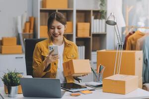 Las pymes asiáticas usan computadoras portátiles para verificar las cajas de envío en línea de pedidos de clientes en casa. Emprendedor de pequeñas empresas pyme freelance. negocio en línea, concepto de trabajo en casa. foto