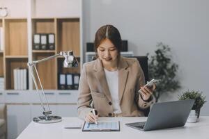 retrato de un contento asiático mujer de negocios utilizando móvil teléfono interior, asiático mujer de negocios trabajando en moderno oficina. foto