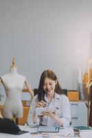 retrato hermosa sonrisa asiático diseñador mujer utilizar computadora en sastre tela Moda pequeño negocio en línea taller. joven propietario puesta en marcha emprendedor. creativo niña textil prenda SME negocio concepto foto