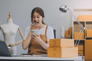 Starting Small business entrepreneur SME freelance, Portrait young woman working at home office, BOX, smartphone, laptop, online, marketing, packaging, delivery, b2b, SME, e-commerce concept.. photo