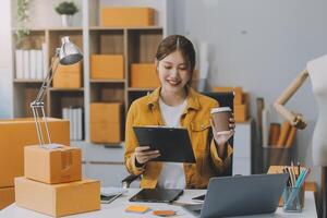 Las pymes asiáticas usan computadoras portátiles para verificar las cajas de envío en línea de pedidos de clientes en casa. Emprendedor de pequeñas empresas pyme freelance. negocio en línea, concepto de trabajo en casa. foto