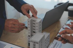 balancing the property sector The real estate agent is explaining the house style to see the house design and the purchase agreement.Wooden house at modern office photo