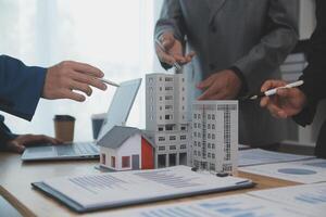 balancing the property sector The real estate agent is explaining the house style to see the house design and the purchase agreement.Wooden house at modern office photo