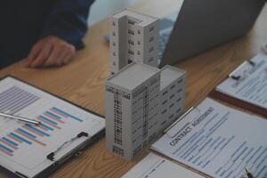 balancing the property sector The real estate agent is explaining the house style to see the house design and the purchase agreement.Wooden house at modern office photo