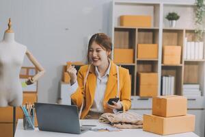 Startup SME small business entrepreneur of freelance Asian woman using a laptop with box Cheerful success Asian woman her hand lifts up online marketing packaging box and delivery SME idea concept photo