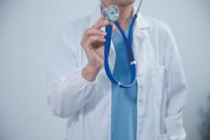 Senior doctor wearing white coat standing holding stethoscope in hands. Older male physician healthcare professional showing medical equipment ready to listen lungs or heart concept. Close up view photo