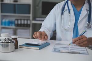 un profesional y enfocado asiático hembra médico en matorrales es trabajando y leyendo médico investigación en su ordenador portátil en su oficina a un hospital. foto