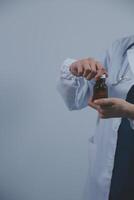 Southeast Asian medical doctor holding a bottle of pills, smiling isolated white background photo