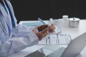 Cropped view of doctor in white coat holding bottle medication, prescribing pills to sick patient via online consultation. Family therapist recommend quality medicines. Healthcare, treatment concept photo