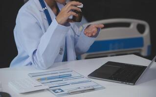 Cropped view of doctor in white coat holding bottle medication, prescribing pills to sick patient via online consultation. Family therapist recommend quality medicines. Healthcare, treatment concept photo