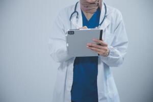 Doctor wearing white coat and watching patient data in Tablet . photo