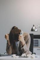 Asian women sitting in an office With stress and eye strain Tired, portrait of sad unhappy tired frustrated disappointed lady suffering from migraine sitting at the table, Sick worker concept photo