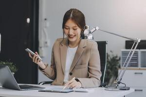 retrato de un contento asiático mujer de negocios utilizando móvil teléfono interior, asiático mujer de negocios trabajando en moderno oficina. foto