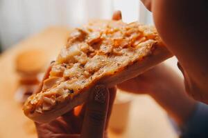 Cropped image of woman holding pizza slice at restaurant photo