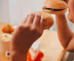 Binge eating disorder concept with woman eating fast food burger, fired chicken , donuts and desserts photo