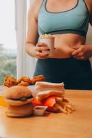 To eat or not. Cheerless plump woman looking at the burger while thinking to eat it or not photo