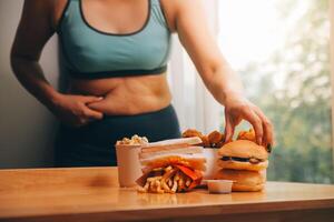 To eat or not. Cheerless plump woman looking at the burger while thinking to eat it or not photo