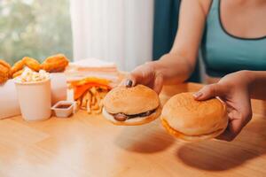 Binge eating disorder concept with woman eating fast food burger, fired chicken , donuts and desserts photo