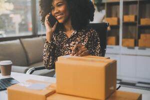 Startup small business entrepreneur or freelance Asian woman using a laptop with box, Young success Asian woman with her hand lift up, online marketing packaging box and delivery, SME concept. photo