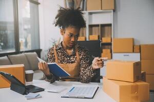 Startup small business entrepreneur or freelance Asian woman using a laptop with box, Young success Asian woman with her hand lift up, online marketing packaging box and delivery, SME concept. photo