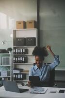 Happy excited successful Asian businesswoman triumphing with a laptop computer smartphone in the workplace office photo