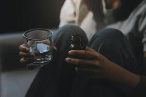 Upset woman frustrated by problem with work or relationships, sitting on couch, embracing knees, covered face in hand, feeling despair and anxiety, loneliness, having psychological trouble photo