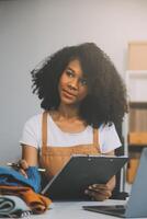 Startup SME small business entrepreneur of freelance Asian woman wearing apron using laptop and box to receive and review orders online to prepare to pack sell to customers, online sme business ideas. photo