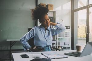 Asian woman working hard in the office having aches and pains in her torso and waist photo