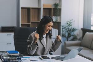 Beautiful Asian girl celebrate with laptop, success happy pose. E-commerce, university education, internet technology, or startup small business concept. Modern office or living room with copy space photo