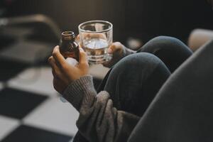 Upset woman frustrated by problem with work or relationships, sitting on couch, embracing knees, covered face in hand, feeling despair and anxiety, loneliness, having psychological trouble photo