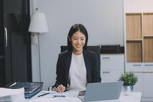 el retrato de una joven mujer asiática independiente está trabajando en su trabajo en una tableta de computadora en una oficina moderna. hacer un informe de análisis contable datos de inversión inmobiliaria, concepto de sistemas financieros y fiscales. foto