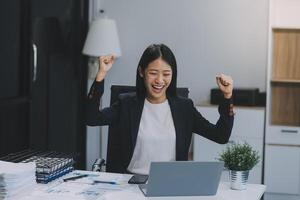 hermosa asiático niña celebrar con computadora portátil, éxito contento pose. comercio electrónico, Universidad educación, Internet tecnología, o puesta en marcha pequeño negocio concepto. moderno oficina o vivo habitación con Copiar espacio foto