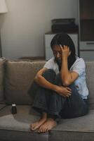 Upset woman frustrated by problem with work or relationships, sitting on couch, embracing knees, covered face in hand, feeling despair and anxiety, loneliness, having psychological trouble photo