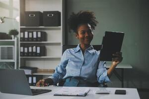 Happy excited successful Asian businesswoman triumphing with a laptop computer smartphone in the workplace office photo