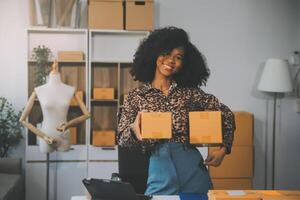 empresaria de pequeñas empresas de nueva creación de una mujer asiática independiente que usa una computadora portátil con una caja de éxito alegre mujer asiática su mano levanta la caja de embalaje de marketing en línea y el concepto de idea de sme de entrega foto