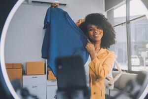 Moda blogger concepto, joven asiático mujer de venta ropa en streaming.startup pequeño negocio pequeño, utilizando teléfono inteligente o tableta tomando recibir y comprobación en oficina foto