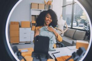 Moda blogger concepto, joven asiático mujer de venta ropa en streaming.startup pequeño negocio pequeño, utilizando teléfono inteligente o tableta tomando recibir y comprobación en oficina foto