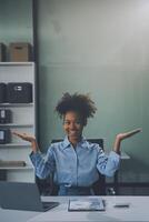 Happy excited successful Asian businesswoman triumphing with a laptop computer smartphone in the workplace office photo