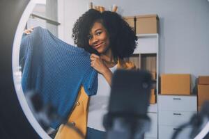 Moda blogger concepto, joven asiático mujer de venta ropa en streaming.startup pequeño negocio pequeño, utilizando teléfono inteligente o tableta tomando recibir y comprobación en oficina foto