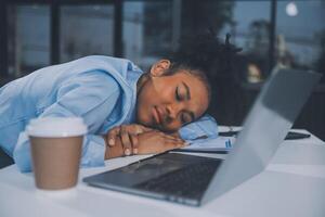 Sad tired young asian lady thinking, sleep at laptop, suffering from overwork, stress in room interior. Deadline, problems in study, work, business, freelance at home new normal with tech photo