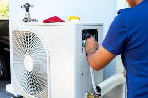 masculino técnico instalando al aire libre unidad de aire acondicionador a frio el casa en el verano. aire compresor, electrónico, caliente verano, alto temperatura, tropical países foto